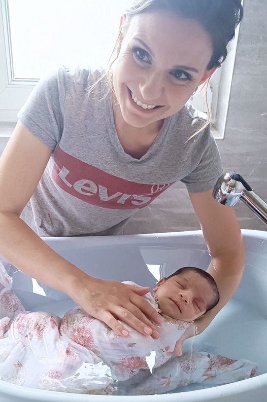 Rachel souriante pendant le bain thérapeutique d'un nouveau-né