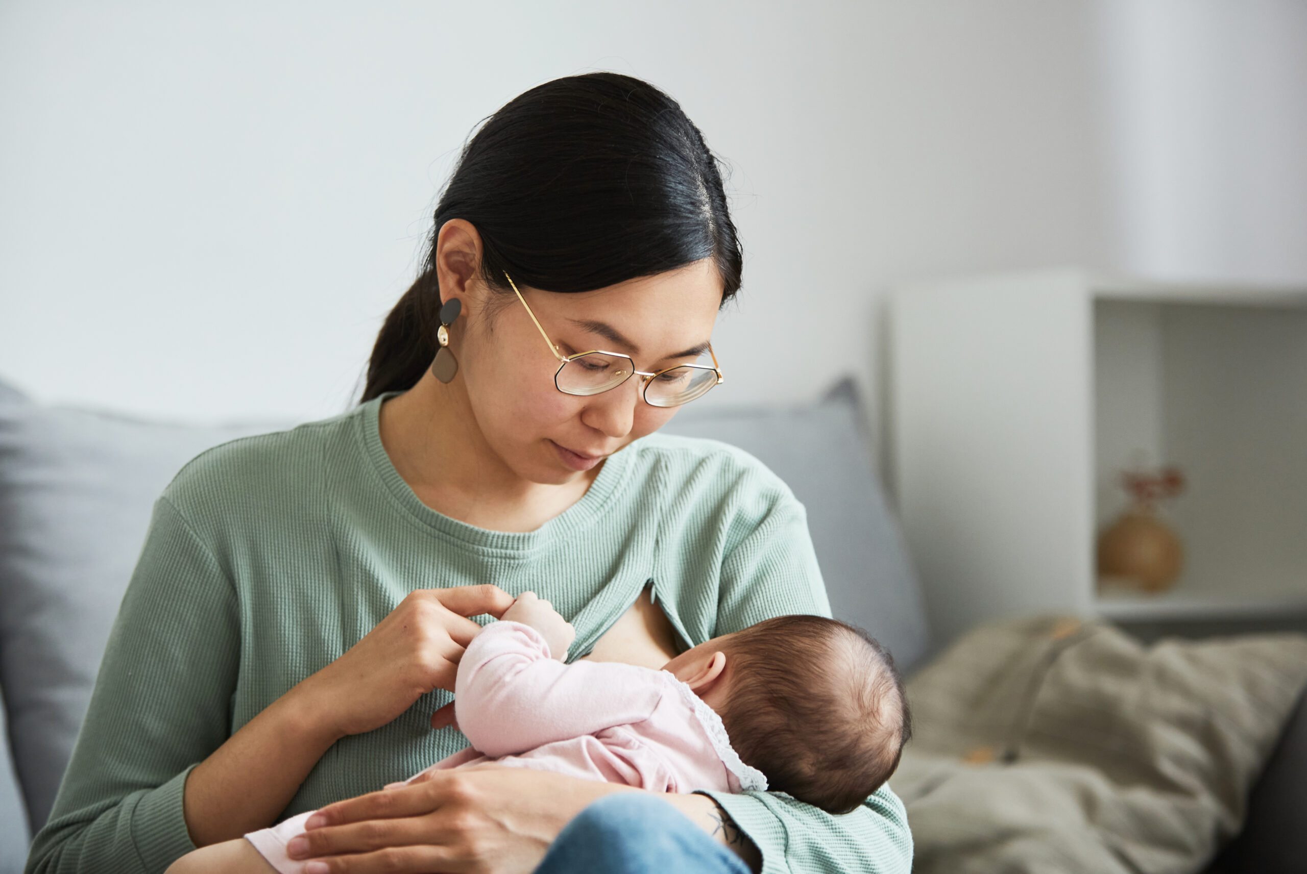 Jeune maman allaitant son bébé à la maison