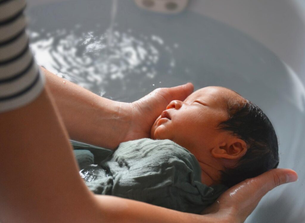 Nouveau-né soutenu dans l'eau chaude pendant son bain thérapeutique
