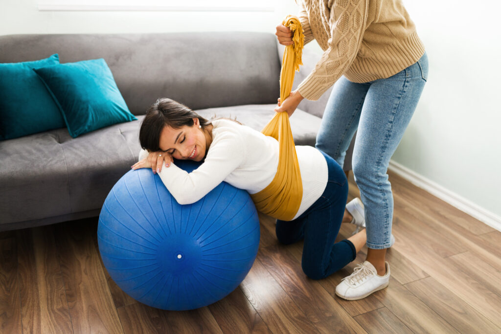 Soin rebozo pendant la grossesse : future maman appuyée sur un ballon, bercée dans un châle