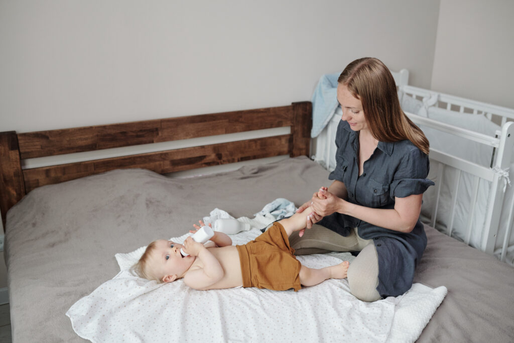 Massage des jambes d'un bébé allongé sur un lit