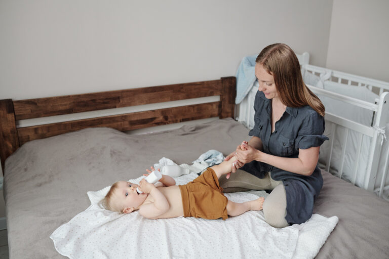 Massage des jambes d'un bébé allongé sur un lit