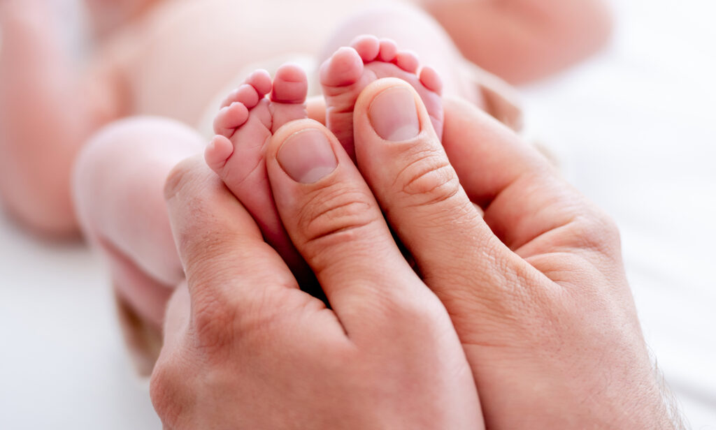 Mains d'adulte tenant les petits pieds d'un bébé
