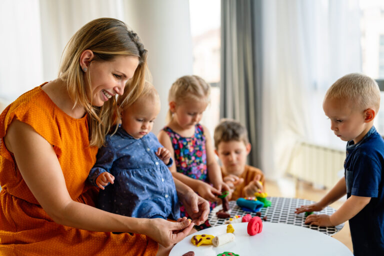 Professionnelle de la petite enfance jouant avec des enfants autour d'une table