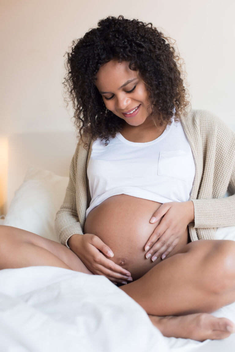 Future maman assise, les mains posées sur son ventre